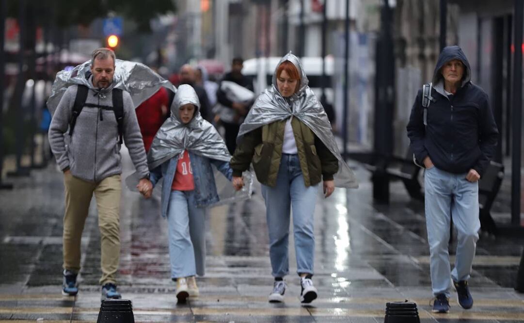 Transeúntes utilizan impermeables improvisados para cubrirse de la lluvia en la CDMX